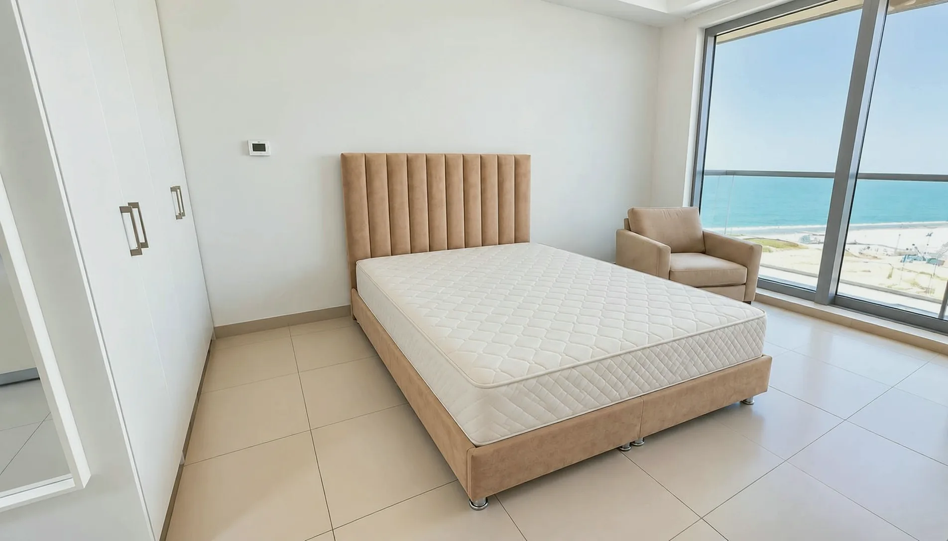 After Furnishing: The studio furnished: an upholstered bed and an armchair by the sea-view window.