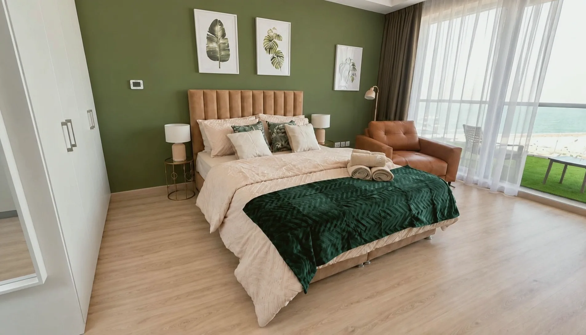 After High-End Airbnb: The studio finished with a green feature wall, wood floor, leather armchair, throw and fresh towels.