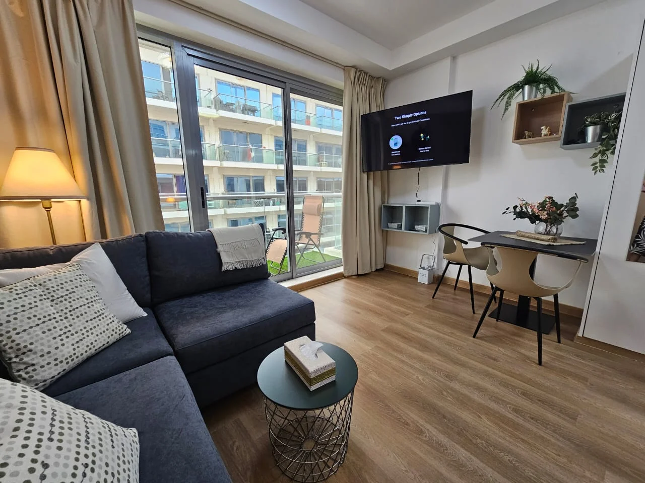 Living room of a BLK-managed apartment: sofa, dining table and a balcony