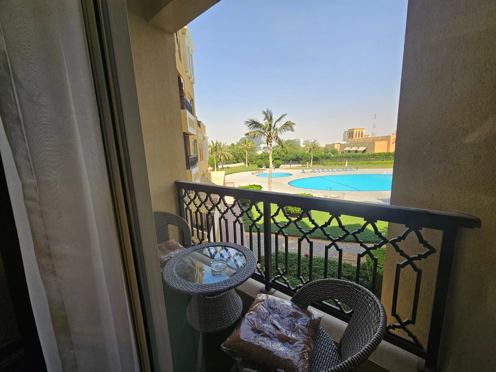 Coastal view from a BLK-managed apartment in Ras Al Khaimah: balcony, palms and the pool